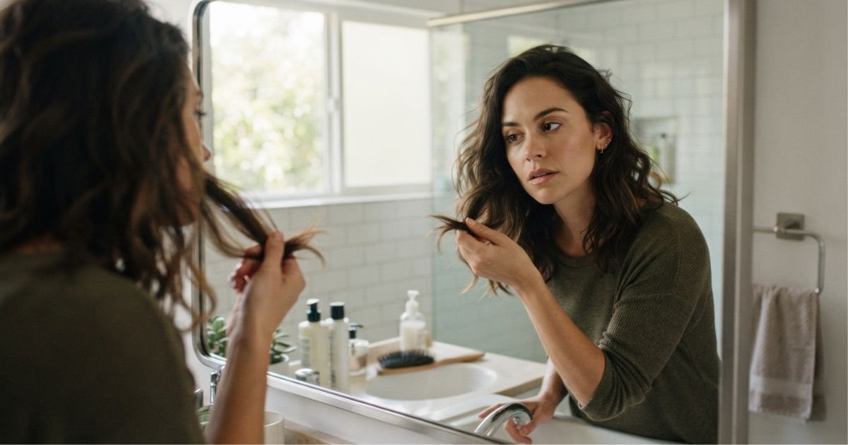 mulher no espelho analisando o proprio cabelo